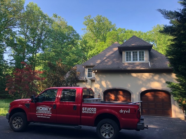 red Robey Stucco specialist truck parked outside of a residential home