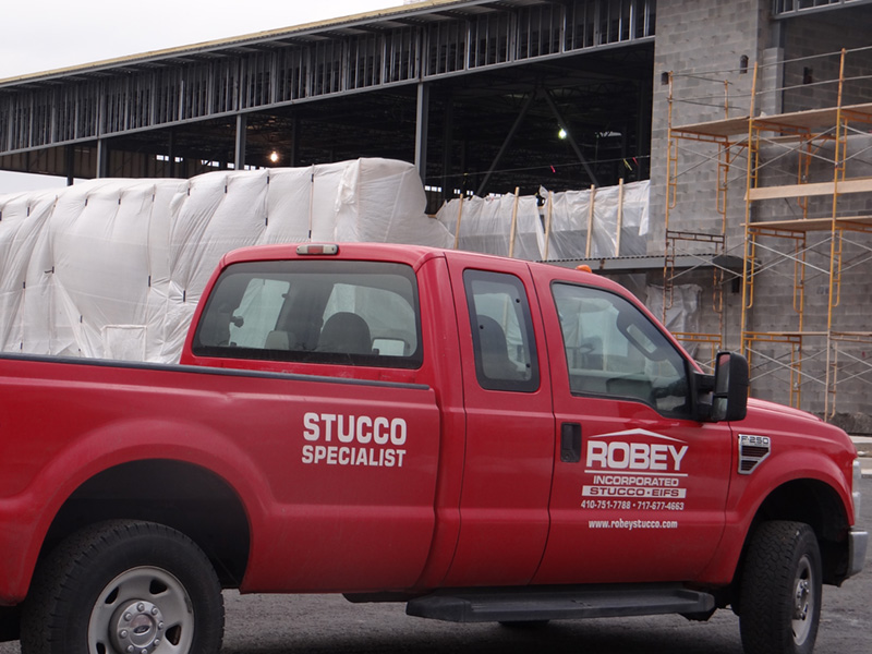 red Robey Incorporated Stucco Specialist truck parked by a building under construction