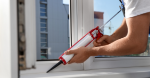 man caulking the exterior of a window